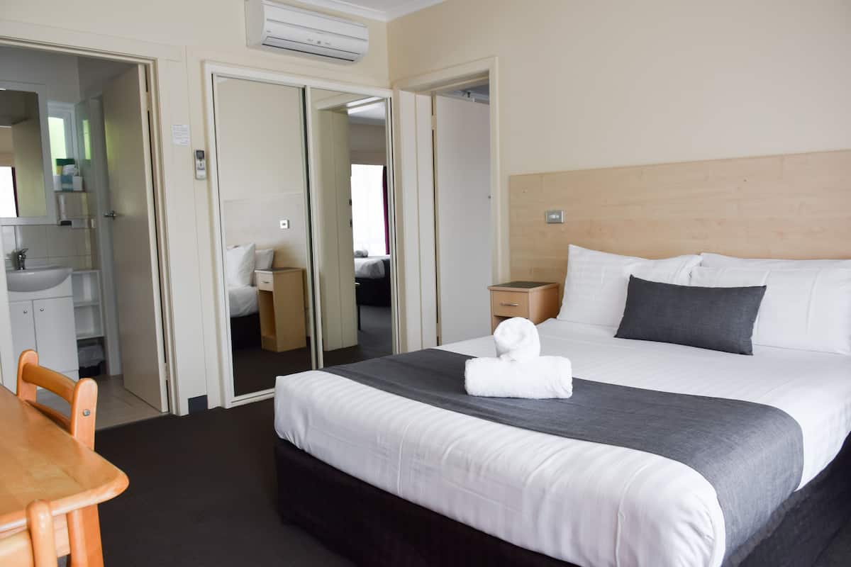 A hotel room with a bed, a desk, a chair, a wardrobe, and a bathroom.