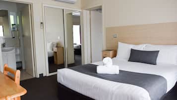 Ett hotellrum med en säng, ett skrivbord, en stol, en garderob och ett badrum.