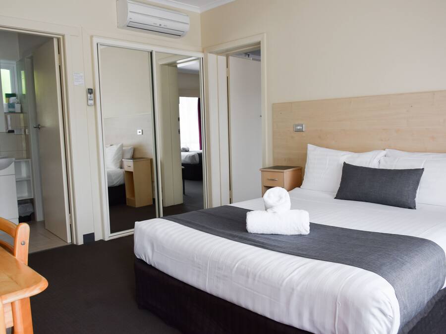 Una habitación de hotel con cama, escritorio, silla, armario y baño.