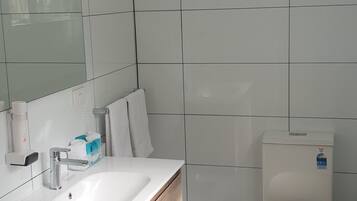 Un baño moderno con lavamanos, espejo y retrete blancos.
