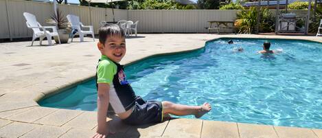 Una piscina al aire libre, sillones reclinables de piscina