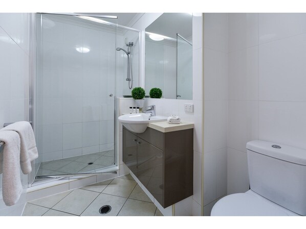 A modern bathroom with a glass shower enclosure, a sink with a mirror, and a toilet.