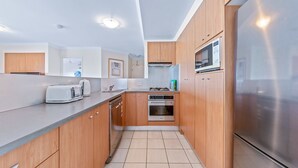Una cocina moderna con armarios de madera, electrodomésticos de acero inoxidable y suelo de baldosas.