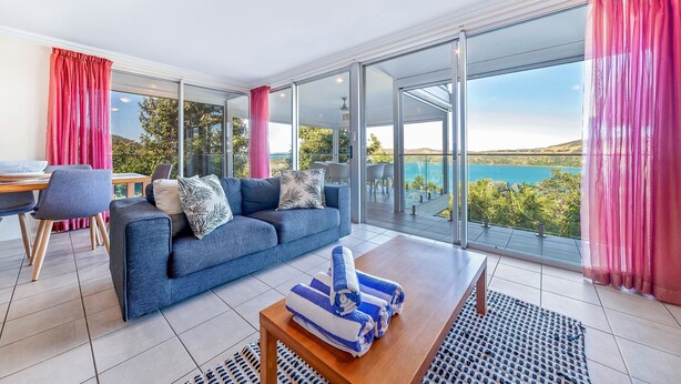 Un salón moderno con sofá, mesa de centro y vistas a una piscina y paisaje.