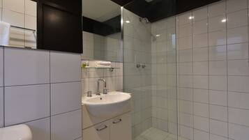 A modern bathroom with a glass-enclosed shower, a white sink, and a mirror above it.