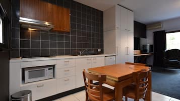 A modern kitchen with a microwave, wooden cabinets, and a dining table with chairs.