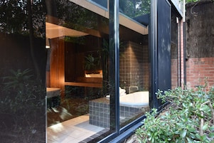 A modern bathroom with a glass enclosure, a bathtub, and a wooden vanity.