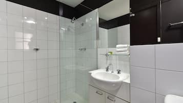 A modern bathroom with a glass-enclosed shower, a white sink, and a black-framed mirror.