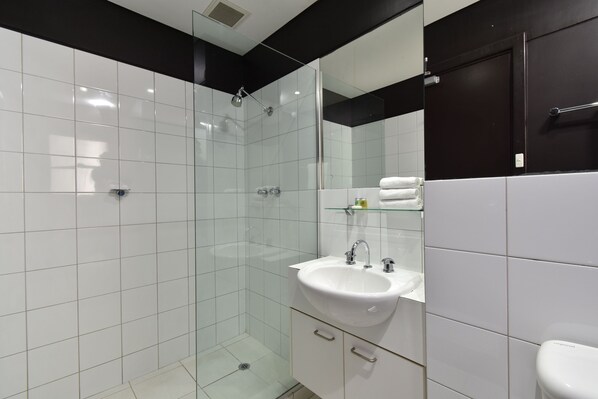 A modern bathroom with a glass-enclosed shower, a white sink, and a black-framed mirror.