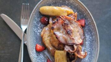 Un plato con un trozo de carne, fruta y una pizca de polvo.