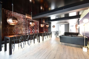 A modern interior with a long dining table, black chairs, and hanging pendant lights.