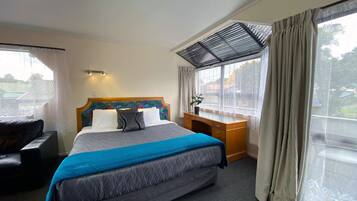 A hotel room with a large bed, a desk, and a window with curtains.