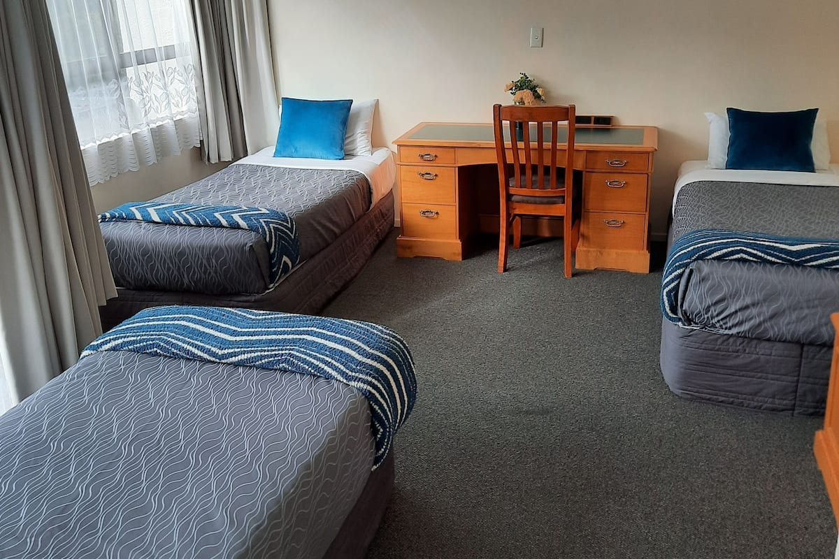 Ein Hotelzimmer mit zwei Einzelbetten, einem Schreibtisch und einem Stuhl.