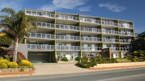A multi-story hotel with balconies, a garage, and landscaped gardens. - Albacore Apartments (Merimbula)