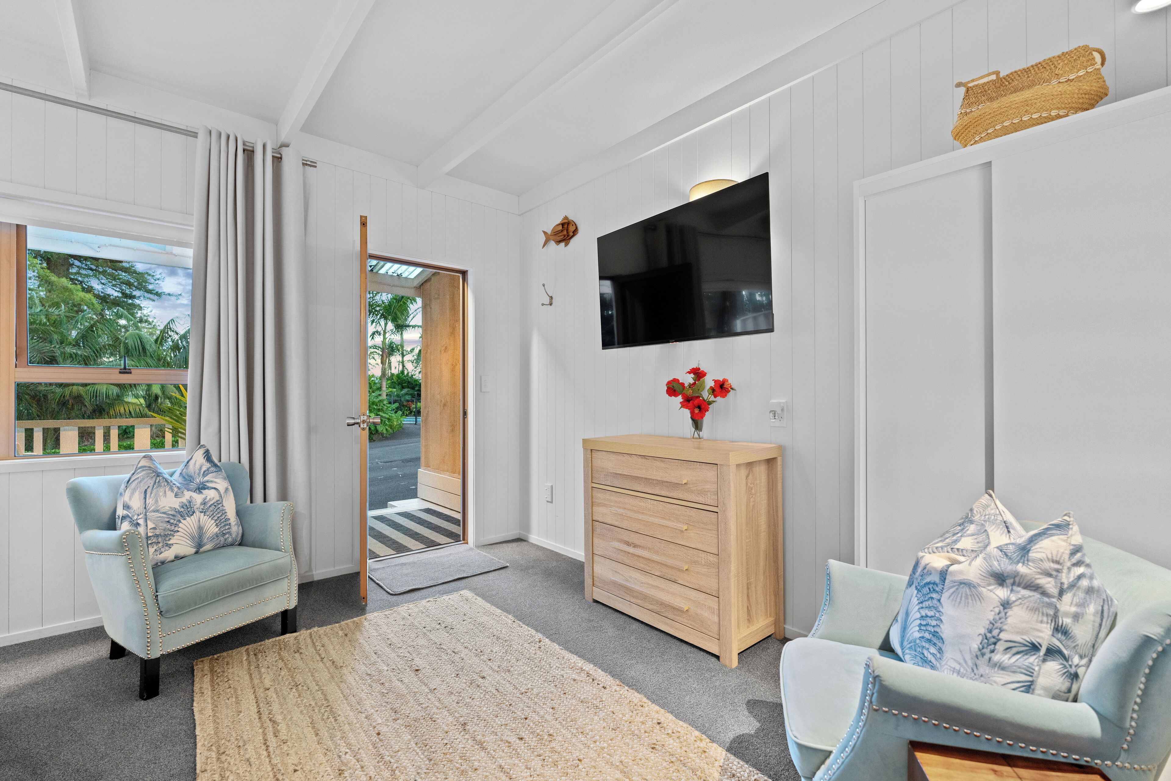 A room with a wooden cabinet, a television, and two armchairs with floral cushions.