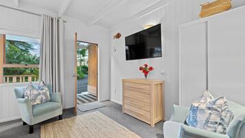 A room with a wooden cabinet, a television, and two armchairs with floral cushions.