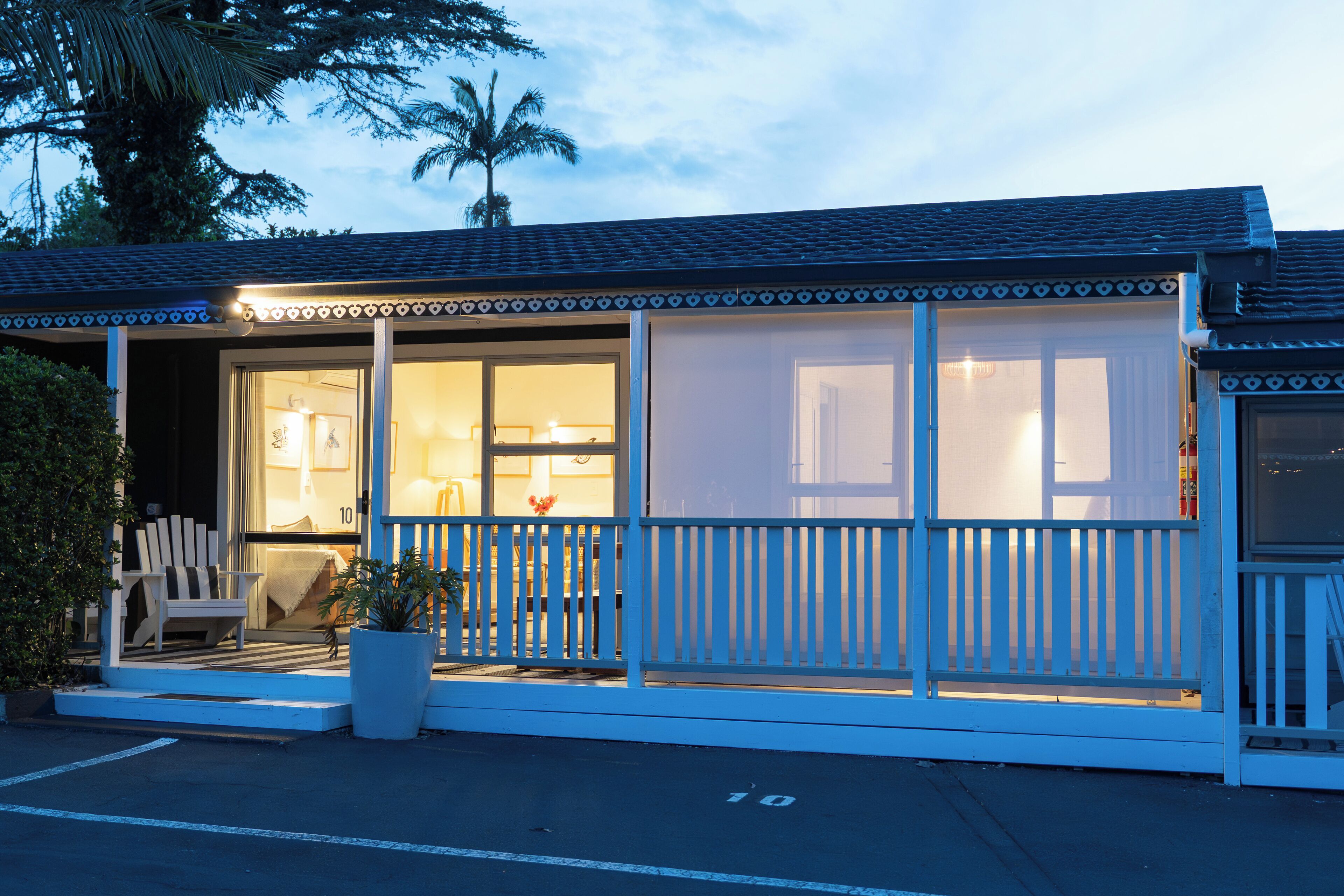 A beachfront hotel with a covered porch, a seating area, and a view of the ocean.