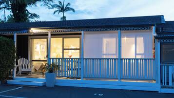 A beachfront hotel with a covered porch, a seating area, and a view of the ocean.