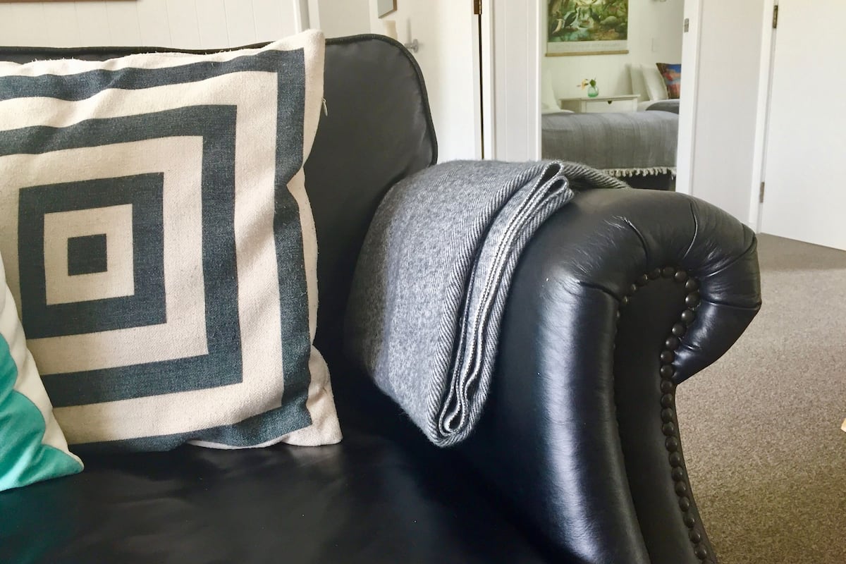 A black leather armchair with a patterned pillow and a folded blanket.