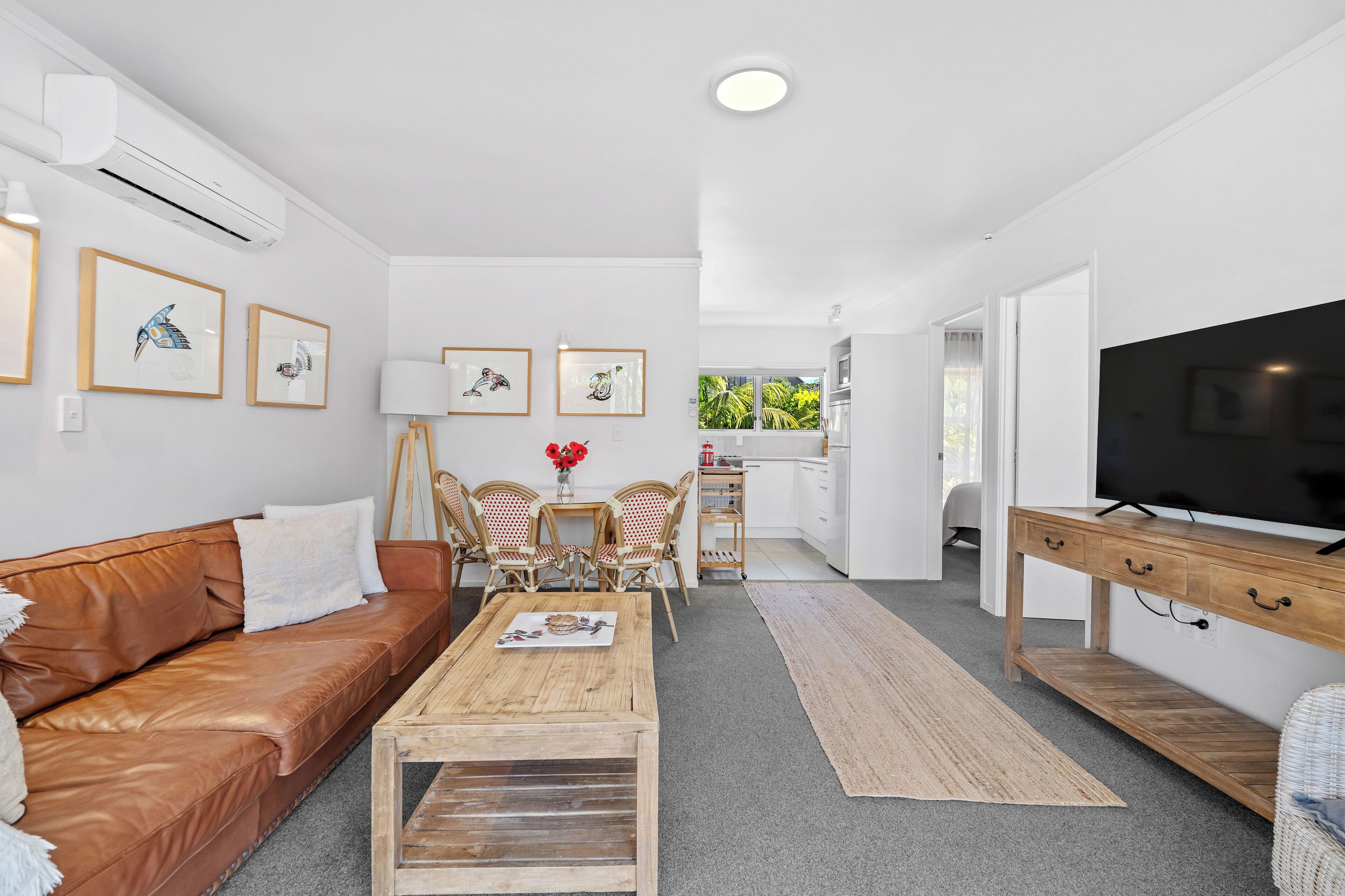 Ein modernes Wohnzimmer mit einem braunen Ledersofa, einem Holztisch und gerahmten Kunstwerken an den Wänden.