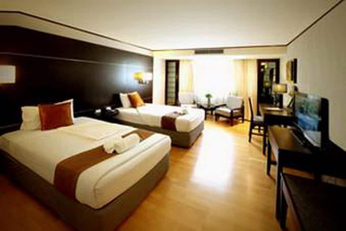 A hotel room with two beds, a desk, a chair, a TV, and a small table.
