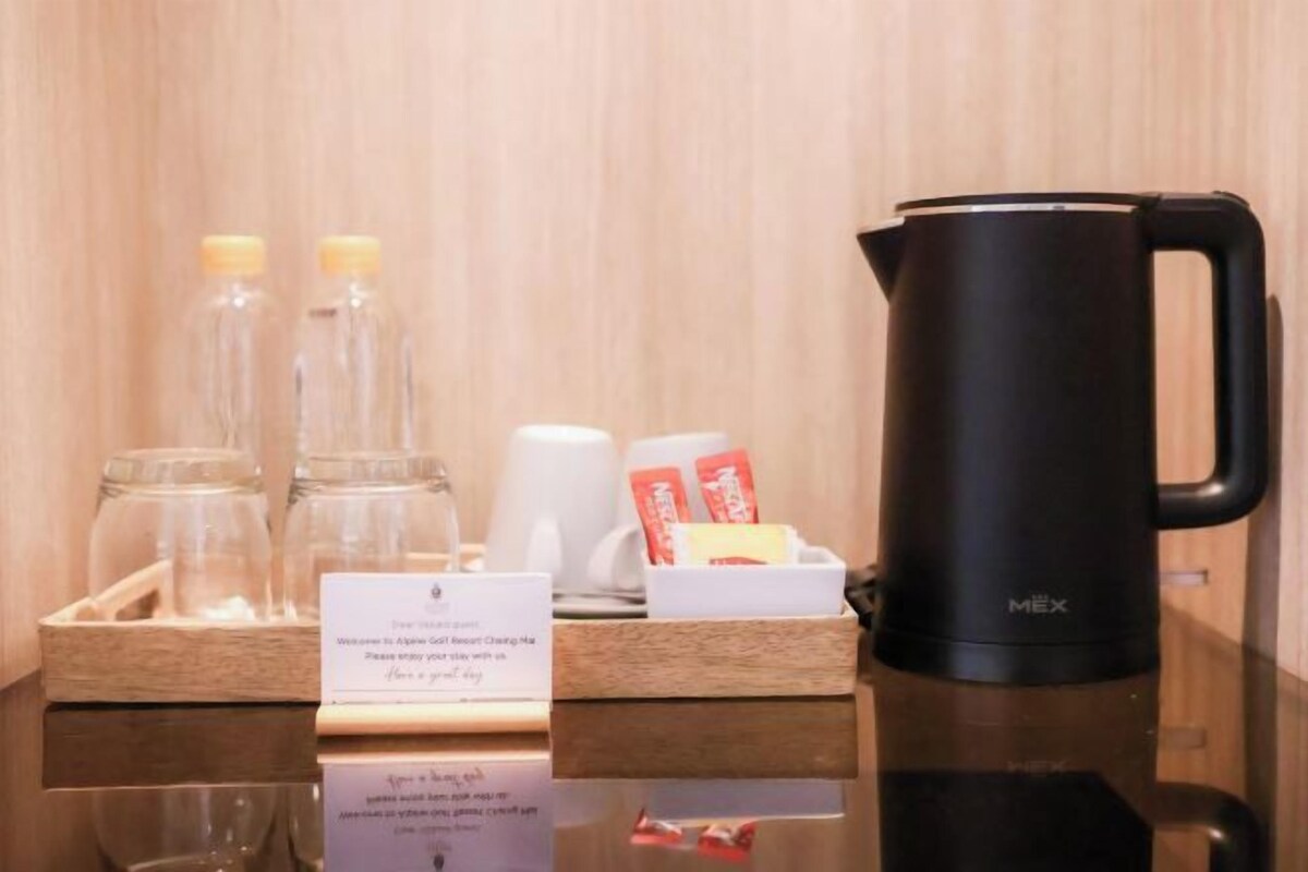 Angolo caffè con una macchina per il caffè nera, due barattoli di vetro con coperchi gialli, una tazza bianca e un vassoio con una confezione di capsule Nespresso.