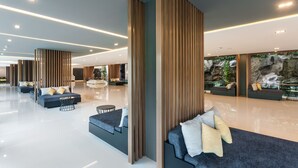 A spacious lobby with modern seating areas, a large rock wall, and a polished floor. - Alpine Golf Resort Chiang Mai (Ban Thi)