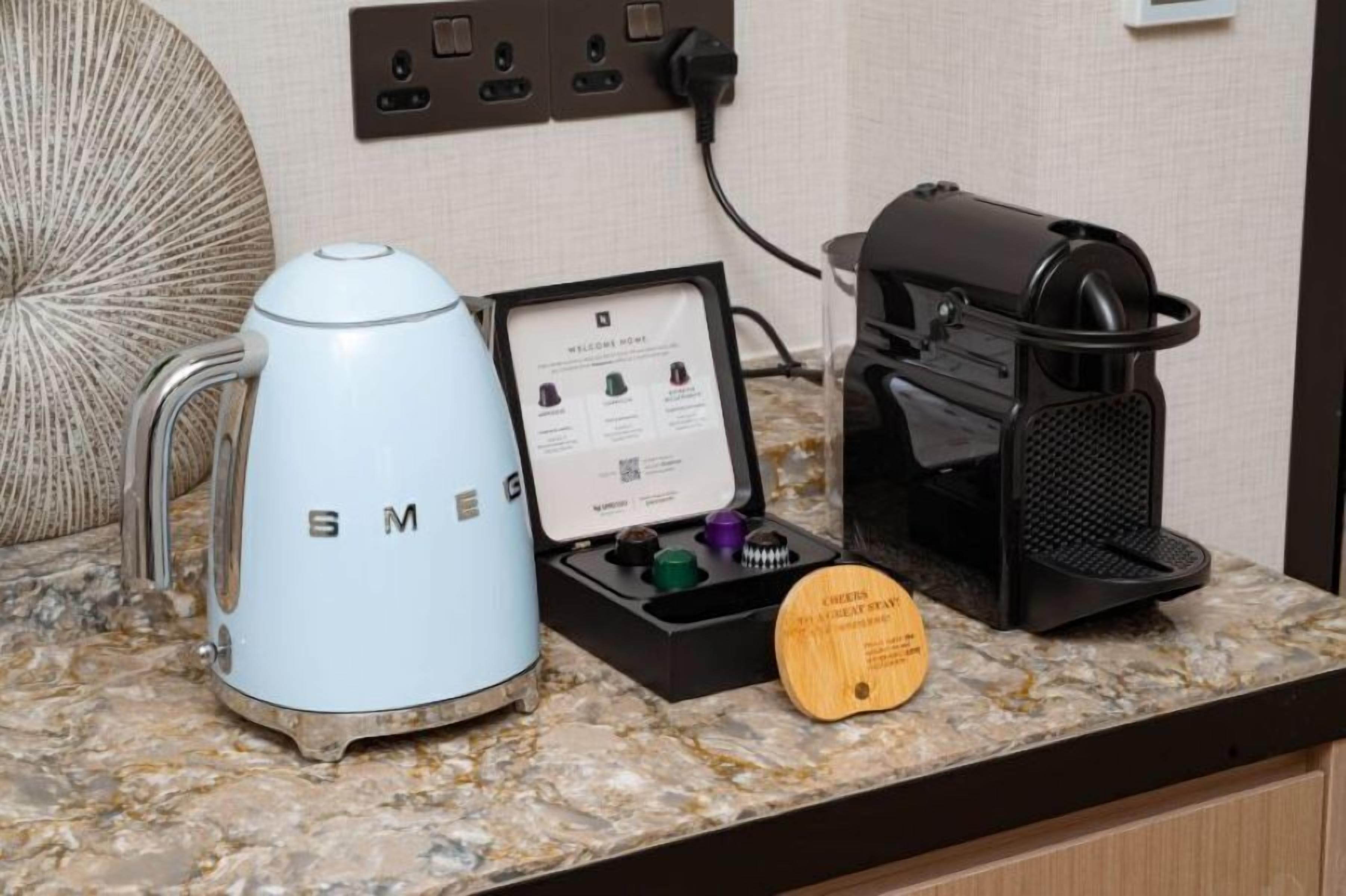 A kitchen counter with a coffee maker, a coffee pod holder, and a wooden coaster.
