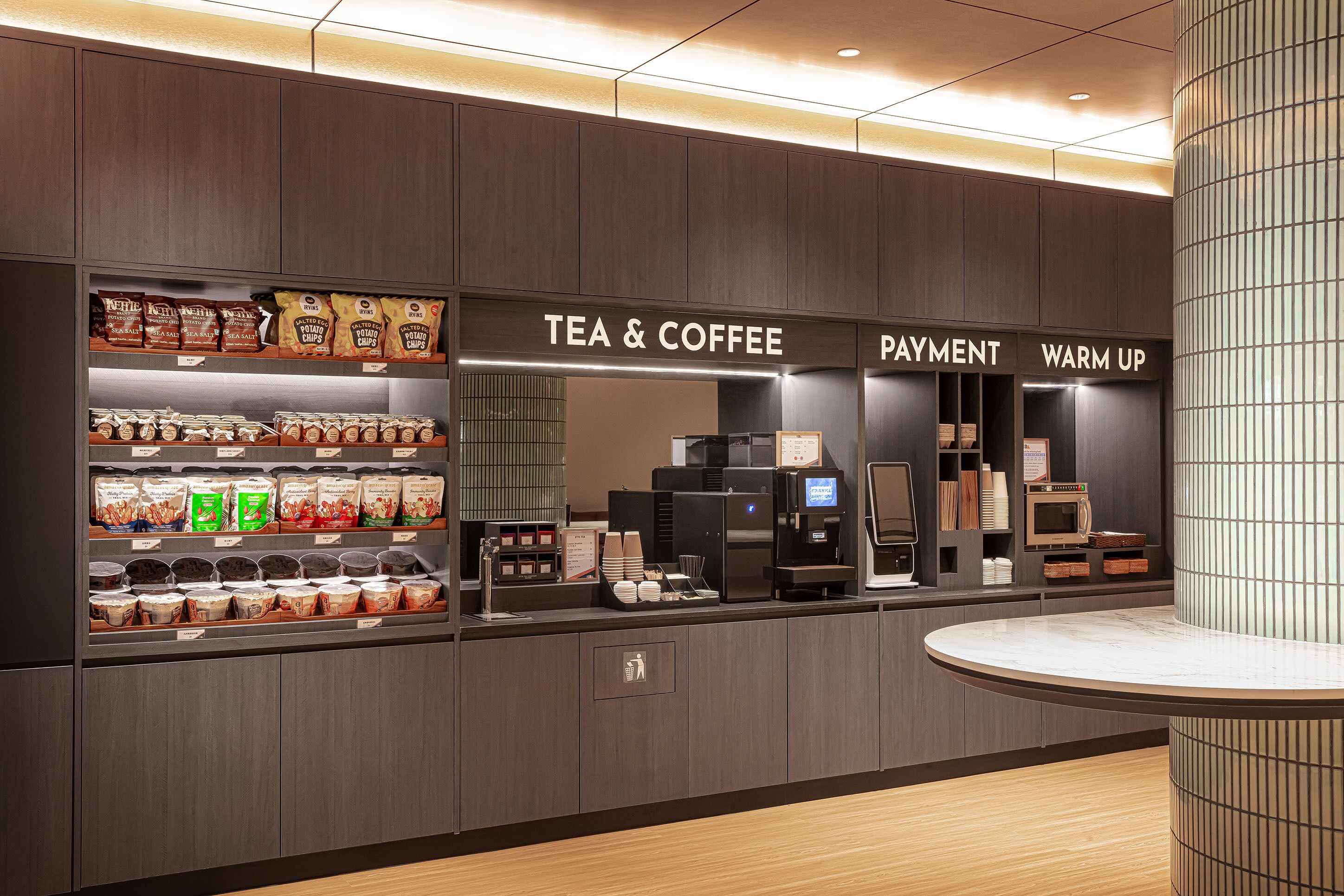 Una estación moderna para té y café con secciones claramente identificadas para pago y precalentamiento.