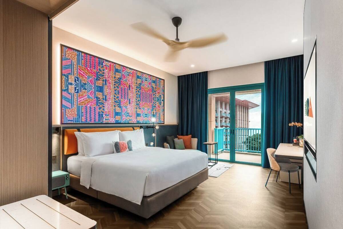 Une chambre d’hôtel moderne dotée d’un grand lit, d’un bureau et d’un balcon avec des rideaux.