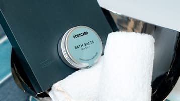 Caixa preta com etiqueta 'POSTCARD BATH SALTS SEA SALTS' e uma toalha branca dentro.