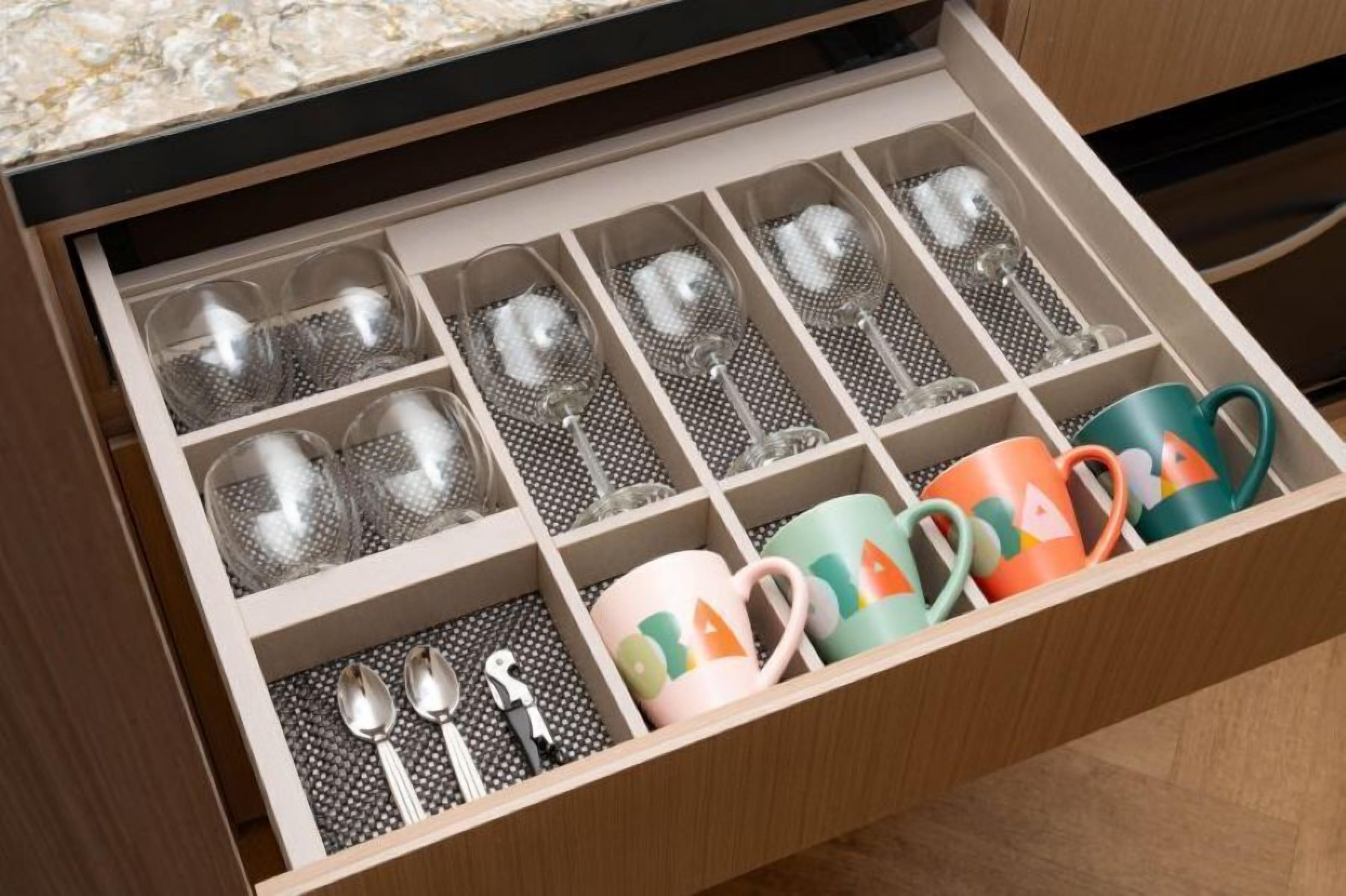A drawer with compartments for glasses, mugs, and cutlery.
