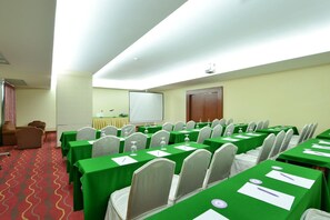 A conference room with green tables, white chairs, a projector screen, and a carpeted floor. - Hip Bangkok (Bangkok)