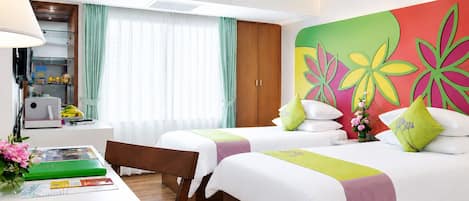 A hotel room with two beds, a desk, a chair, a lamp, a window with curtains, and a colorful wall decoration.