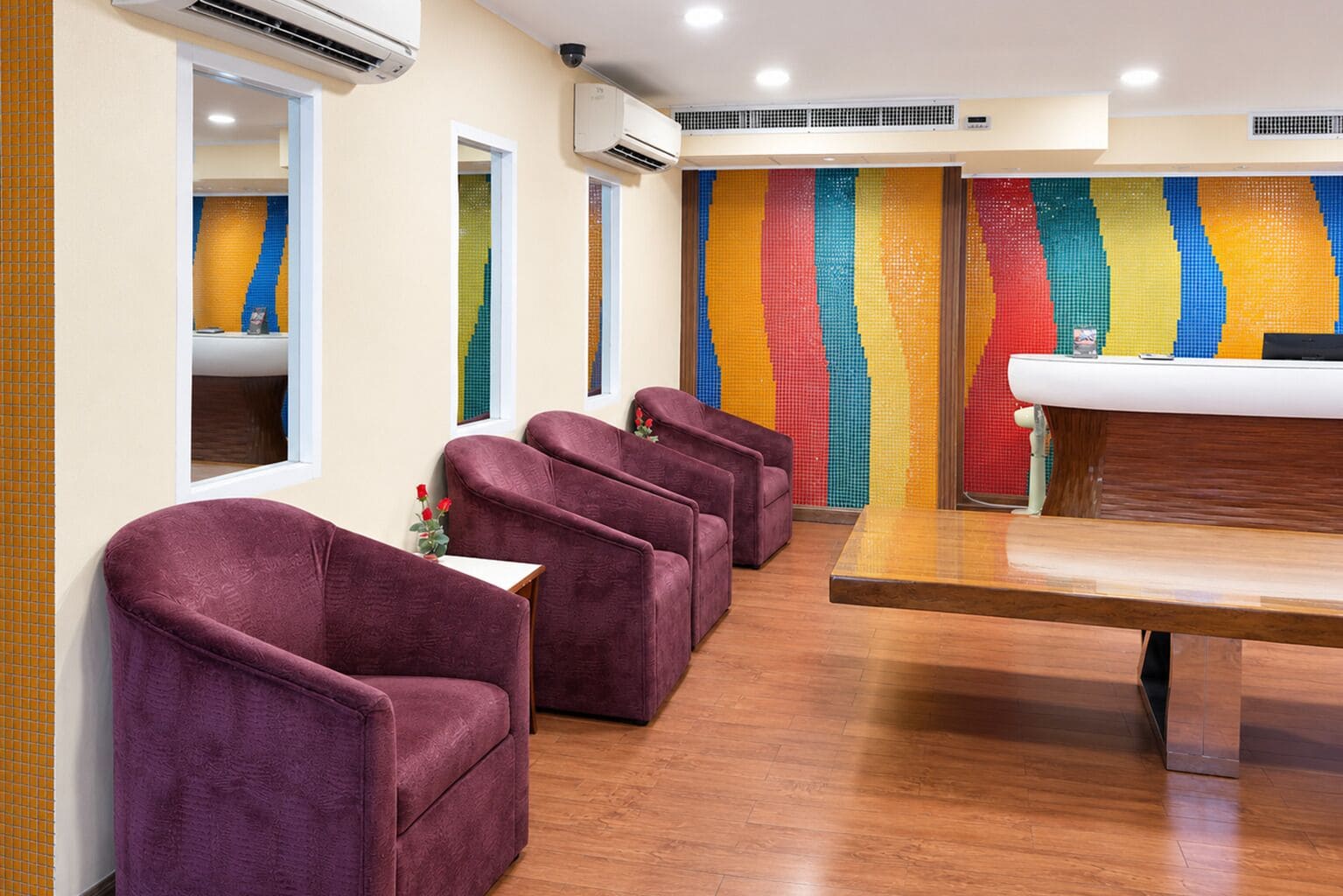 A room with purple chairs, a wooden table, and a colorful wall.