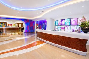 A modern hotel reception area with a curved reception desk, a digital display wall, and a polished floor. - Hip Bangkok (Bangkok)