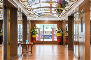 A hotel lobby with a wooden floor, a round table, and two large flower arrangements. - Hip Bangkok (Bangkok)