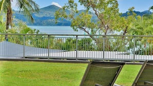 A balcony with two metal chairs, a view of a lake, and surrounding greenery. - Hibiscus 006 (Whitsundays)