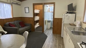 Un espacio habitable compacto con kitchenette, comedor y una zona de descanso separada con literas.