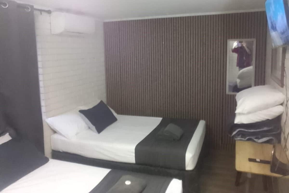 A hotel room with a bed, a small desk, a mirror, and a television.