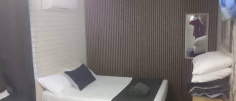 A hotel room with a bed, a small desk, a mirror, and a television.