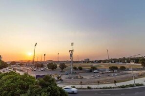 A parking lot with cars and a sports field with floodlights.