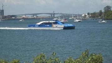 En blå snabbåt med texten ”Daytona” på sidan, som färdas på ett vattenområde med andra båtar och en bro i bakgrunden.