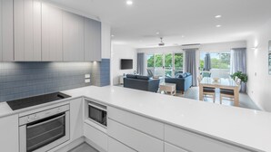 A modern kitchen with a large island, built-in oven, and a dining area with a table and chairs.