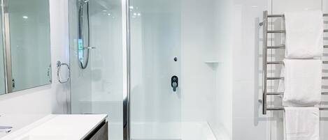 A modern bathroom with a glass-enclosed shower, a white bathtub, and a vanity with a mirror.