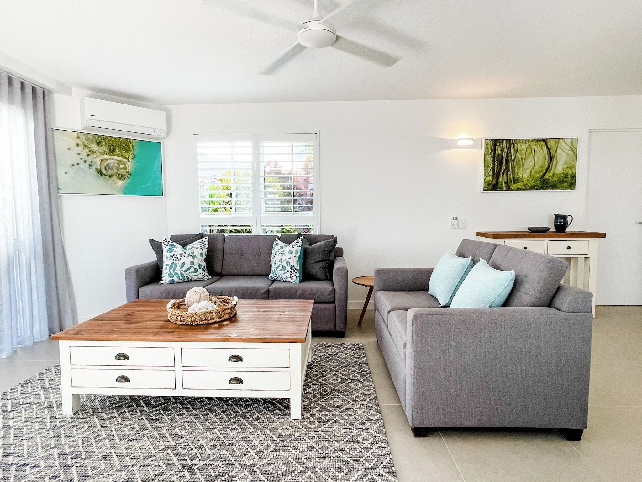A modern living room with a grey sofa, a white coffee table, and a patterned rug.
