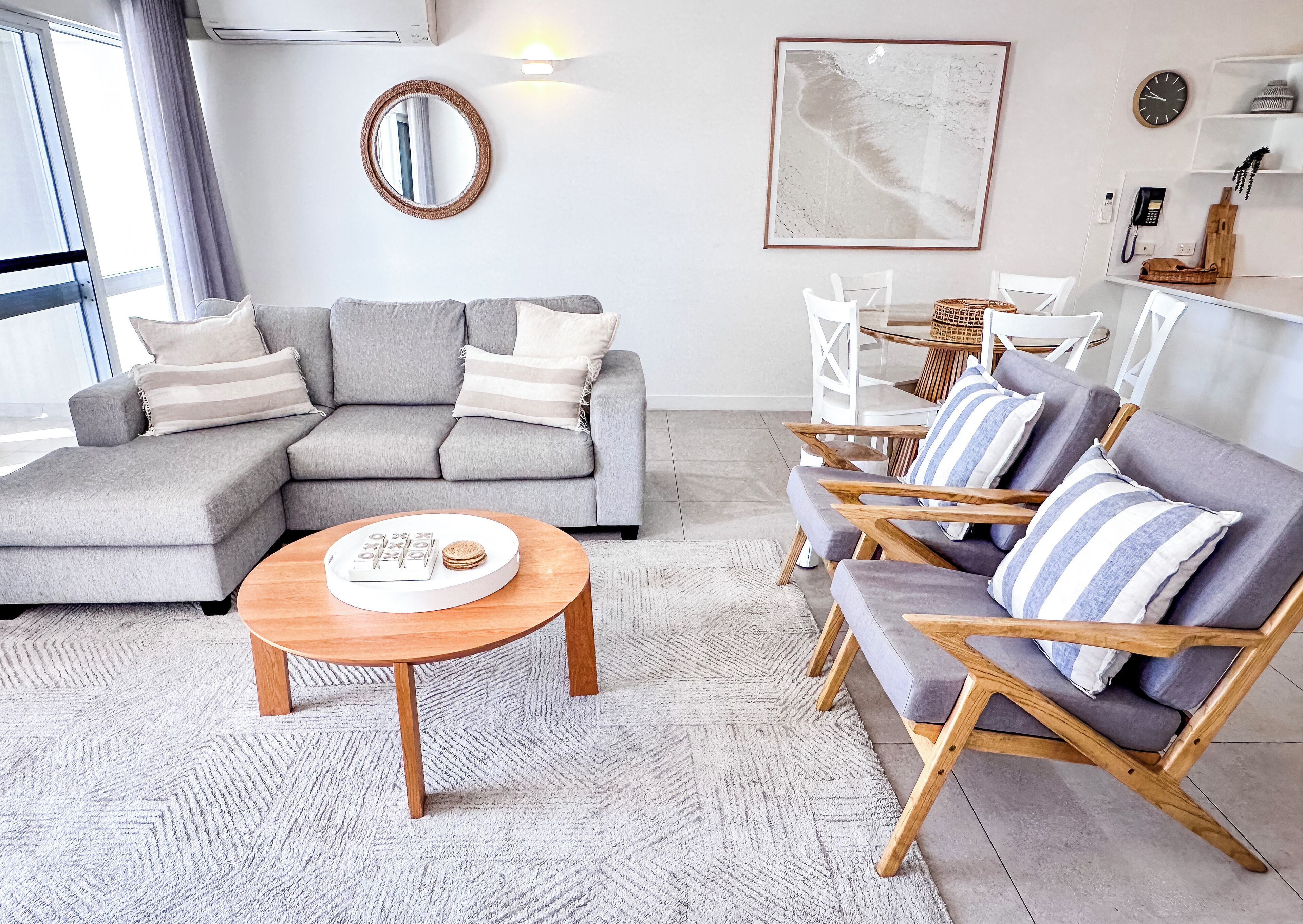 Una sala de estar moderna con un sofá seccional gris, una mesa de centro de madera y sillones a rayas.