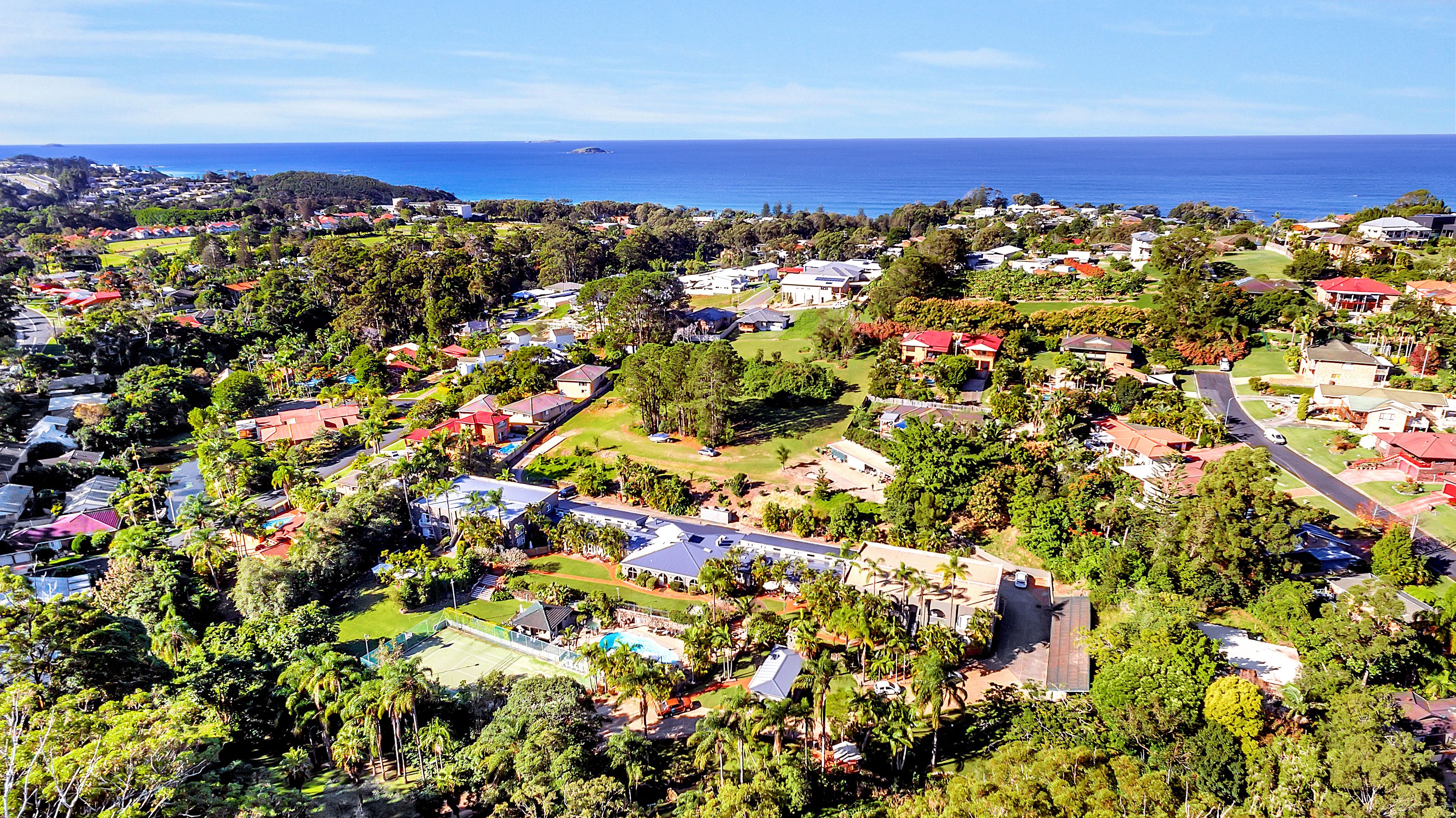 An aerial view of a residential area with houses, roads, and a large body of water in the background.