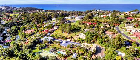 An aerial view of a residential area with houses, roads, and a large body of water in the background.