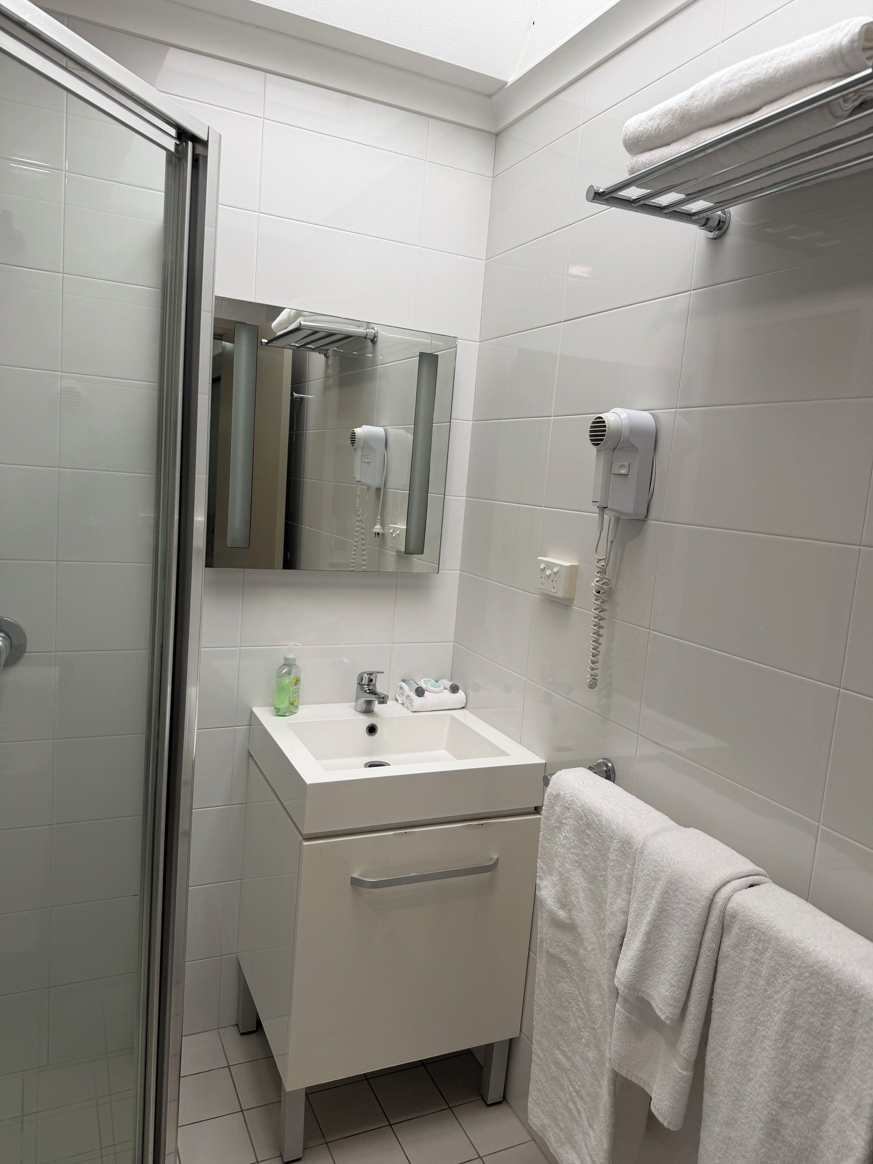 A bathroom with a white sink, mirror, and towel rack.